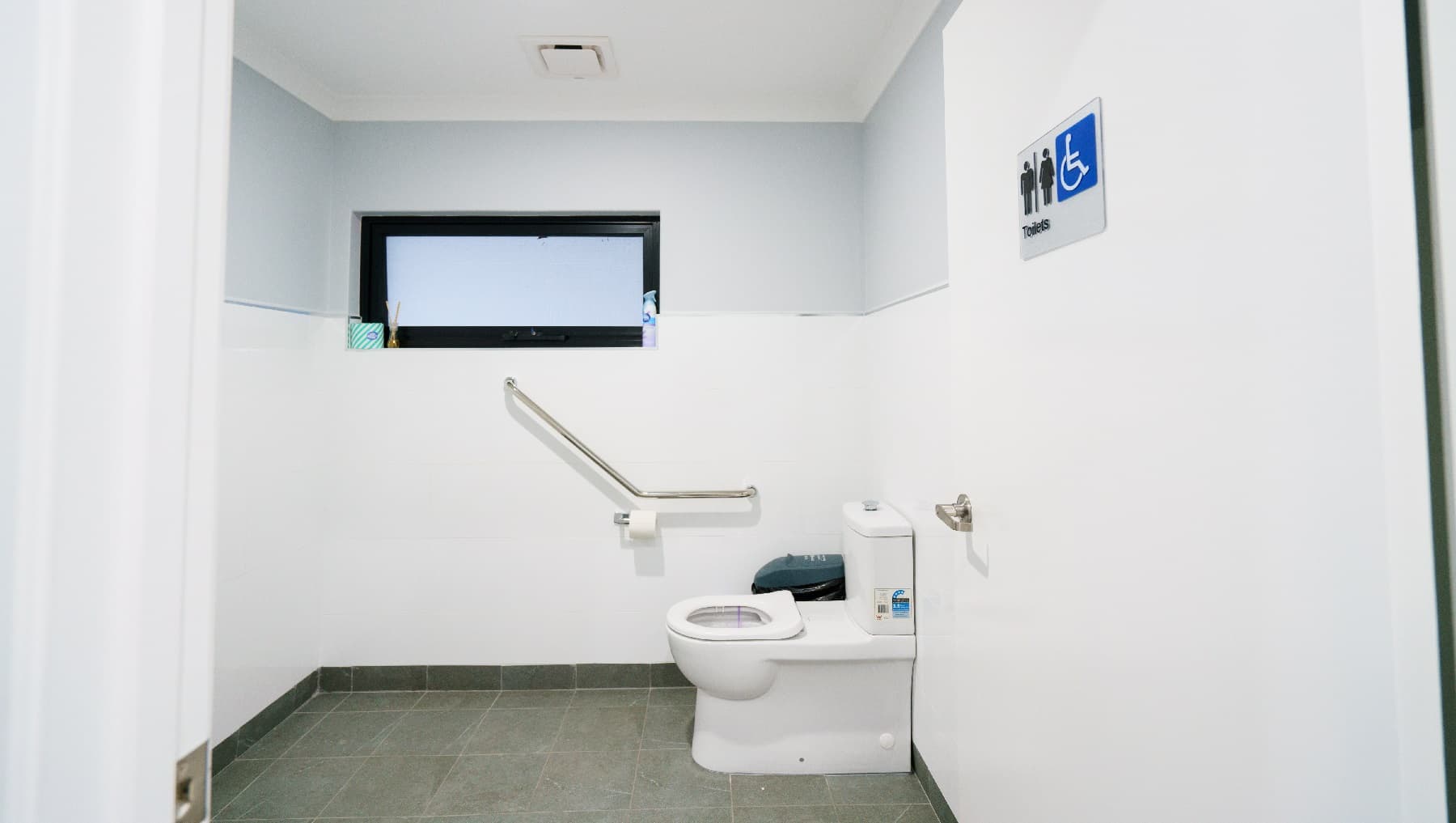 The clinic’s toilet is almost all-white including the door, except the rails of the window which are painted black. This is an all-gender toilet as signified by the signage posted on the door. The toilet is wide enough to accommodate anyone, even guests with disabilities. There’s a rubbish bin in the corner and a roll of tissue paper mounted on the wall. There is also a stainless grab rail situated next to the toilet.